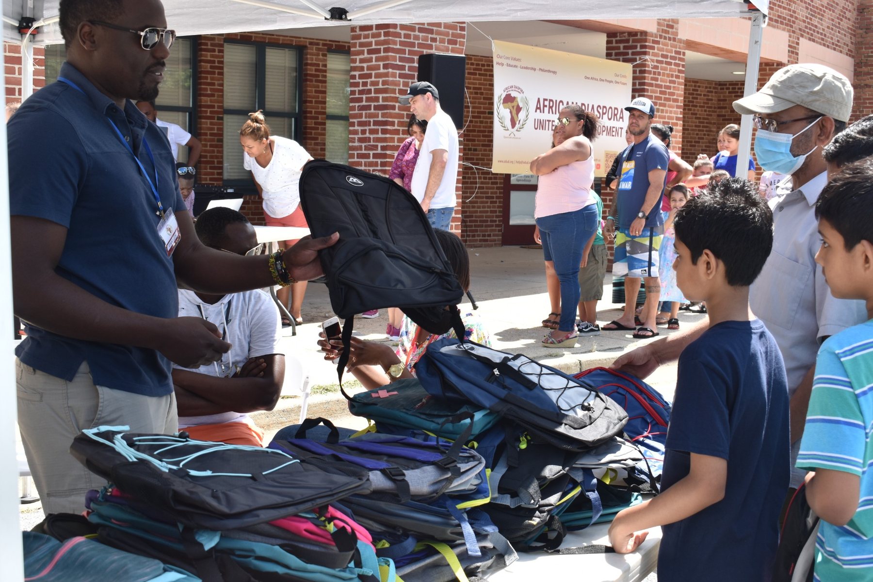 ADUD volunteer helping children select backpacks during the Back-to-School Backpack Bash