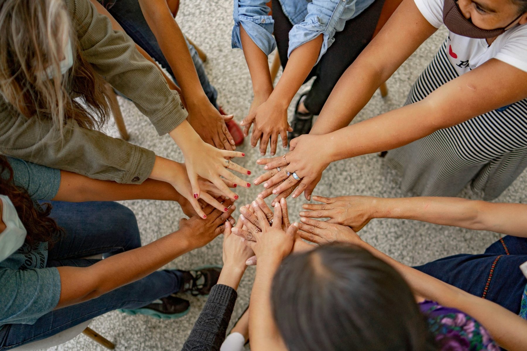 A diverse group placing their hands together in a circle